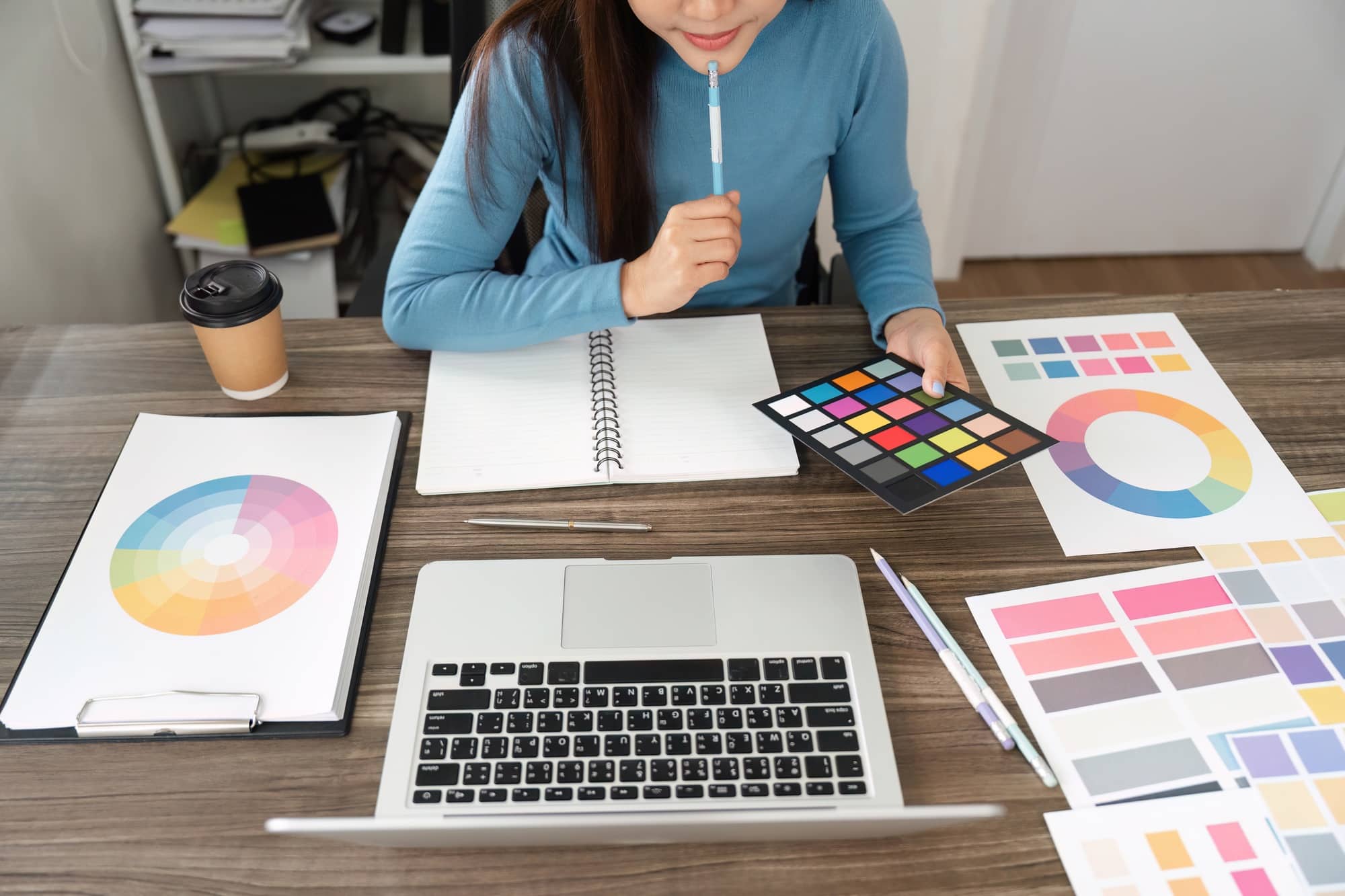 A design enthusiast engaged in color palette selection using color charts.